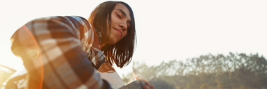 Young man smiling with eyes closed as he plays guitar in the sun
